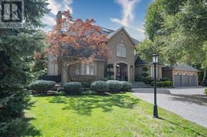 Toronto (St. Andrew-Windfields) apartment for rent - A large house with a well-manicured lawn and a tree with orange leaves in front.