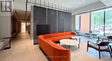 Toronto (North St. James Town) condo for rent - A modern living room with a large orange sofa and a glass partition wall.