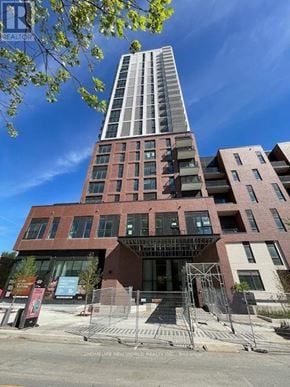 Toronto (Regent Park) condo for rent - A tall building with a glass facade is the centerpiece of a modern residential complex.