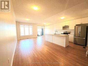 Brantford townhouse for rent - A spacious kitchen with white cabinets and a wooden floor.