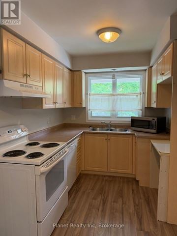 Guelph (Downtown) townhouse for rent - A kitchen with wooden cabinets and a white stove top oven.