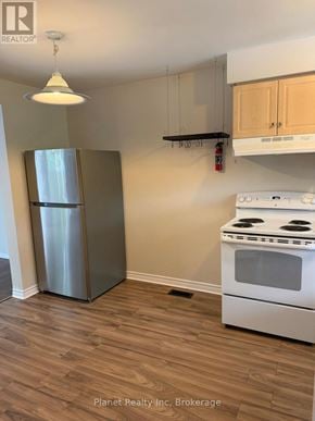 Guelph (Downtown) townhouse for rent - A kitchen with a stainless steel refrigerator and a white stove top oven.