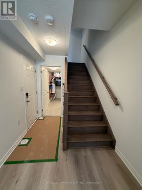 Kitchener townhouse for rent - A hallway with a staircase and a doorway leading to a room with a shelf.