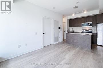 Hamilton (Riverdale) condo for rent - A modern kitchen with a white door and a microwave above the stove.