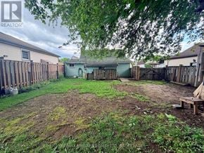 Niagara Falls (Downtown) apartment for rent - A backyard with a dirt area and a wooden fence.