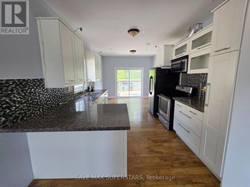 Barrie (Ardagh) apartment for rent - A kitchen with white cabinets and a black and white tiled backsplash.