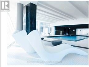 Vaughan (Concord) condo for rent - A modern interior with a pool and a white chair.