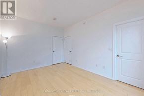 Toronto (Bay Street Corridor) condo for rent - A room with white walls and wooden flooring, with a light on the left and a door on the right.