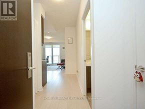 Mississauga (Hurontario) condo for rent - A hallway with a door on the left and a chair in the background room.