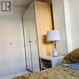 Toronto (Centennial Scarborough) apartment for rent - A bedroom with a bed, a nightstand with a lamp, and a wardrobe.