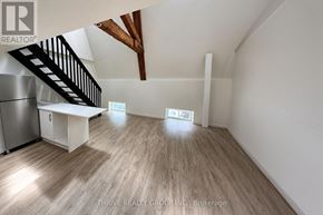 Strathroy-Caradoc (Nw) multi-family for rent - A spacious room with wooden flooring and a staircase leading to the upper level.