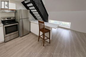 Strathroy-Caradoc (Nw) multi-family for rent - A kitchen with a stainless steel refrigerator, oven, and a wooden chair.