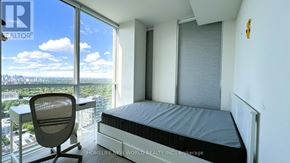 Toronto (Annex) condo for rent - A bedroom with a large bed and a desk with a chair in front of a window overlooking a cityscape.