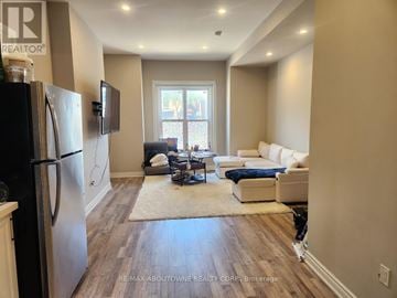 Hamilton (Stinson) fourplex for rent - A kitchen with a refrigerator and a living room with a couch and a television.