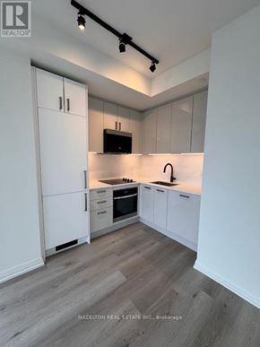 Toronto (Kensington-Chinatown) condo for rent - A kitchen with white cabinets and a wooden floor.