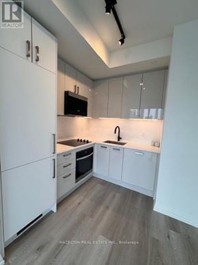 Toronto (Kensington-Chinatown) condo for rent - A modern kitchen with white cabinets and a wooden floor.