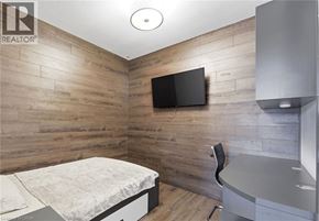 Waterloo condo for rent - A bedroom with a bed, chair, and a television on the wall.