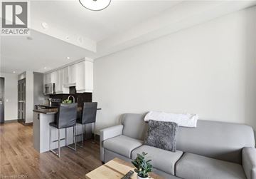 Waterloo condo for rent - A modern living room with a grey couch and a kitchen area in the background.