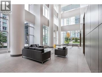 Vancouver apartment for rent - A modern living room with a black sofa and a grey armchair.