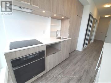 Toronto (Church-Yonge Corridor) condo for rent - A modern kitchen with wooden cabinets and a black stove top.