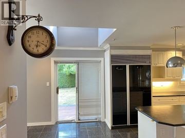 Vancouver apartment for rent - A kitchen with a black fridge and a clock hanging from the ceiling.