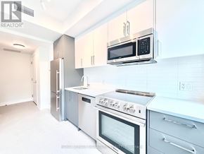 Toronto (University) condo for rent - A modern kitchen with stainless steel appliances and white cabinets.