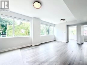 Toronto (University) condo for rent - A spacious room with white walls and a large window overlooking a green area.