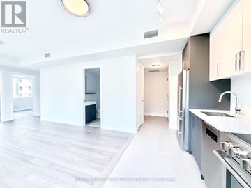 Toronto (University) condo for rent - A modern kitchen with white cabinets and a stainless steel refrigerator.