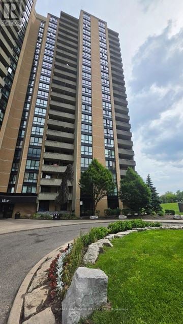 Toronto (Brookhaven-Amesbury) condo for rent - A tall building with many windows is surrounded by a grassy area and a sidewalk.