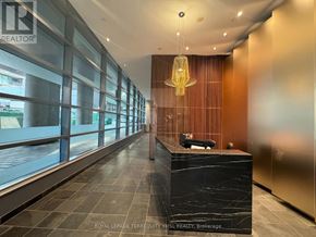Toronto (Waterfront Communities) condo for rent - A long hallway with a black reception desk and a hanging light fixture.