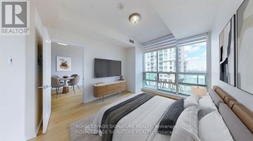 Mississauga (Fairview) condo for rent - A bedroom with a large bed and a balcony overlooking a city.