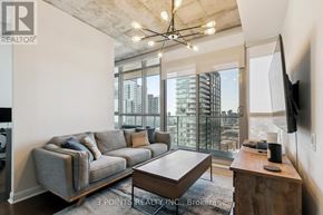 Toronto (Waterfront Communities) condo for rent - A living room with a grey couch, a wooden coffee table, and a flat screen TV mounted on the wall.