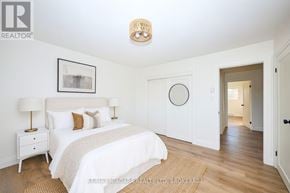 Welland (Lincoln/Crowland) multi-family for rent - A bedroom with a large bed, a nightstand, and a framed picture on the wall.