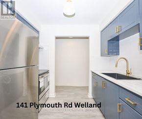 Welland (Lincoln/Crowland) multi-family for rent - A kitchen with blue cabinets and a stainless steel refrigerator.