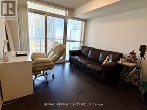 Toronto (Mount Pleasant West) condo for rent - A living room with a brown couch and a chair with a computer desk in front of a window.