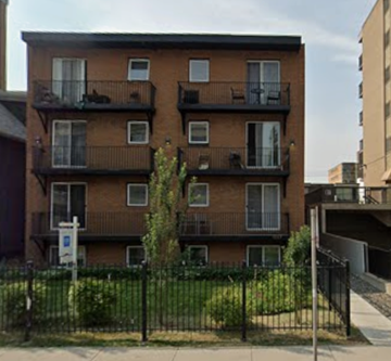 Calgary apartment for rent - A brown building with black railings and a small tree in front.