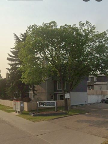 Edmonton apartment for rent - A tree stands in front of a house with a sign on the lawn.