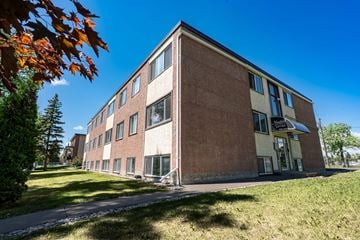 Edmonton apartment for rent - A large brick building with a green lawn in front.