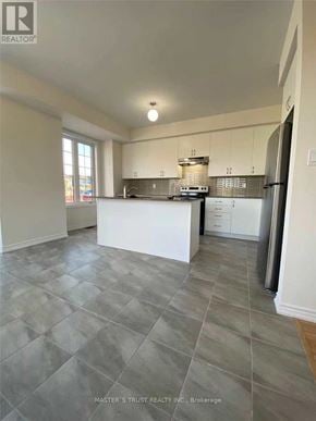 Whitby (Lynde Creek) townhouse for rent - A kitchen with a white island and a refrigerator.