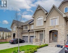Oakville (Bc Bronte Creek) townhouse for rent - A large, two-story house with a stone facade and a garage is for sale.