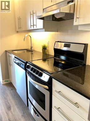 Grimsby condo for rent - A modern kitchen with black countertops and white cabinets.