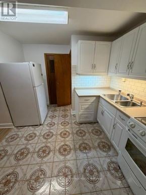 Toronto (Highland Creek) apartment for rent - A kitchen with white cabinets and a rug on the floor.