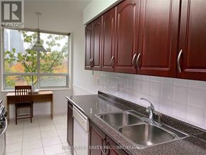 Toronto (Bendale) condo for rent - A kitchen with brown cabinets and a window overlooking a tree.