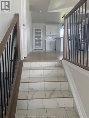 Lakeshore apartment for rent - A hallway with marble tiled floors and wooden stairs.