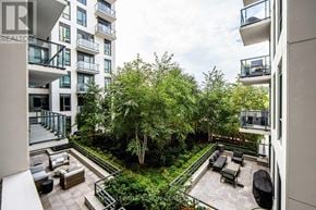 Toronto (Casa Loma) condo for rent - A balcony overlooks a courtyard with a tree and seating area.