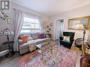 Toronto (The Beaches) apartment for rent - A living room with a grey couch, a glass coffee table, and a rug with the words "Forget the World" on it.