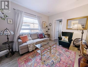 Toronto (The Beaches) apartment for rent - A living room with a grey couch, a glass coffee table, and a rug with the words "Forget the World" on it.