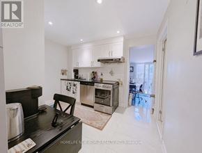 Toronto (The Beaches) apartment for rent - A modern kitchen with white cabinets and a black countertop.