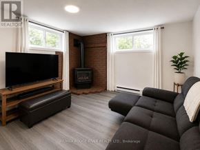 Welland (Prince Charles) apartment for rent - A living room with a black couch, a wooden entertainment center, and a fireplace.