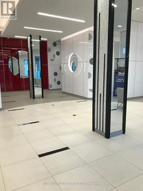 Toronto (Woburn) condo for rent - A glass door with a metal frame is in the foreground of a white tiled floor.